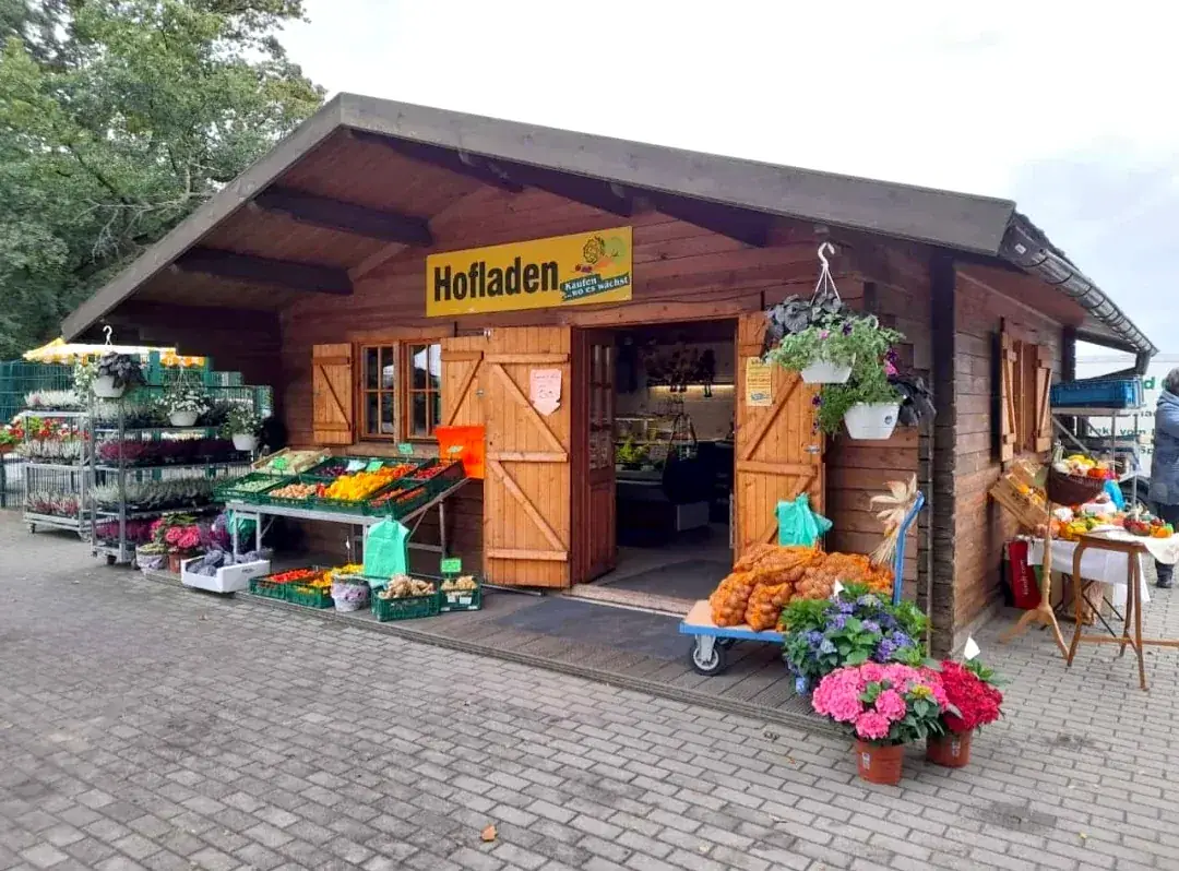 Hofladen in Lübben: Holzhütte mit Auslagen voller Obst, Gemüse und Blumen